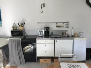 eine Küche mit weißen Schränken und einem schwarzen Herd in der Unterkunft La petite Escarpolette in Arzon