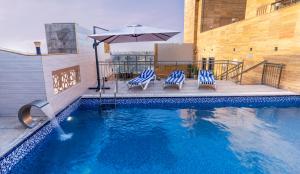a swimming pool with two chairs and an umbrella at Iridium 70 Hotel in Jeddah