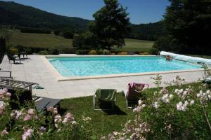 a swimming pool in a yard with chairs and flowers at Chambres d'hôtes de charme Le Pradel in Monceaux-sur-Dordogne