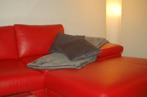 Un sofá de cuero rojo con dos almohadas. en Ländlich ruhig 10 km vor Rostock, en Dummerstorf
