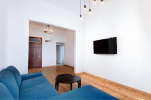 un salon avec un canapé bleu et une télévision dans l'établissement The WHITE APARTMENT - Bogoridi Main Street, à Bourgas