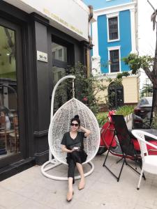 una mujer sentada en una silla blanca en ROSY HẠ LONG HOTEL, en Ha Long
