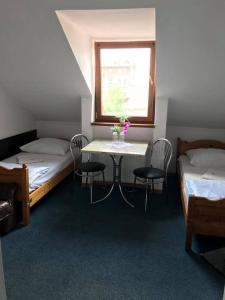 a room with two beds and a table with chairs at Hotel Gryf in Gryfice