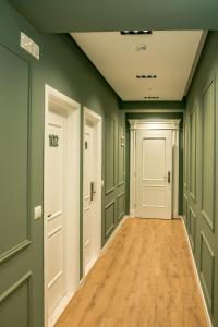 un couloir vide avec des murs verts et du parquet dans l'établissement ODA Aparthotel Shkodër, à Shkodër