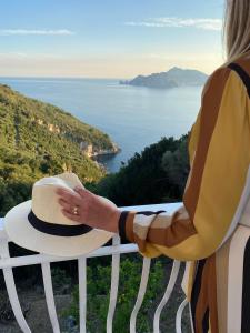 a woman holding a hat on a balcony overlooking the ocean at Acquamarina Accommodation in Massa Lubrense