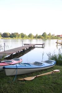 un gruppo di canoe sedute sull'erba vicino a un molo di Szum Muzy Ruś Mała a Ostróda