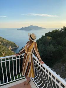 a woman standing on a balcony overlooking the ocean at Acquamarina Accommodation in Massa Lubrense