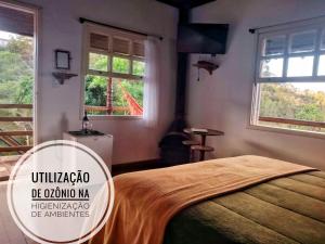 a bedroom with a bed in a room with windows at Pousada Vila de Gaia in Lavras Novas