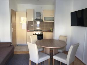 a small kitchen with a wooden table and chairs at Petros Apartments Pag in Pag