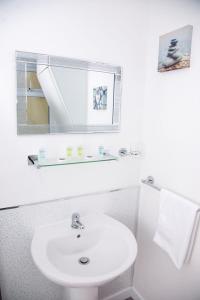 ein Badezimmer mit einem weißen Waschbecken und einem Spiegel in der Unterkunft The Retreat Guest House on Plymouth Hoe in Plymouth