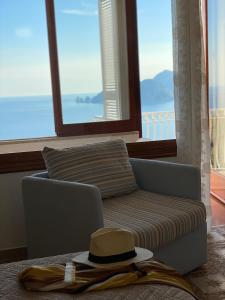a hat sitting on a couch in front of a window at Acquamarina Accommodation in Massa Lubrense