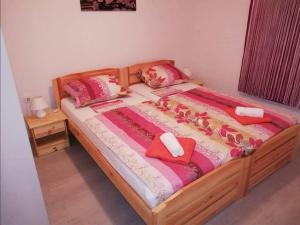 um quarto com uma cama de madeira e almofadas cor-de-rosa em Apartman Tin em Vir
