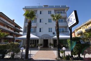 a hotel with palm trees in front of a building at Hotel Atenea Golden Star in Caorle