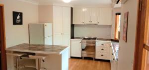 a kitchen with white cabinets and a white refrigerator at Treetops Hideaway Albury in Albury