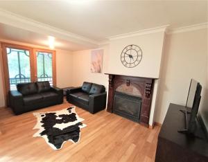 uma sala de estar com lareira e um relógio na parede em Treetops Hideaway Albury em Albury