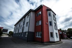 un edificio rojo y blanco al lado de una calle en Apartament u Miecia en Mielno