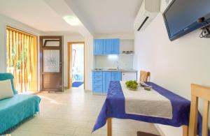 Habitación con mesa y cocina con armarios azules. en Apartman ANTICA, en Vantačići