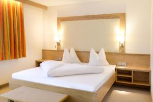 Schlafzimmer mit einem weißen Bett und einem großen Spiegel in der Unterkunft Ferienhotel Elvira in Thiersee