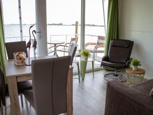 een woonkamer met een tafel en stoelen en een balkon bij Houseboat uitzicht over veluwemeer, natuurlokatie, prachtige vergezichten in Biddinghuizen
