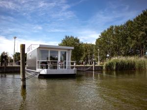 uma casa-barco amarrada a uma doca num rio em Houseboat uitzicht over veluwemeer, natuurlokatie, prachtige vergezichten em Biddinghuizen