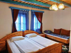 a bedroom with two beds and two windows at Casa Toth in Vişeu de Sus