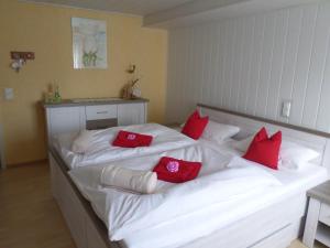 ein großes weißes Bett mit roten Kissen darauf in der Unterkunft Dorfblüte in Albstadt
