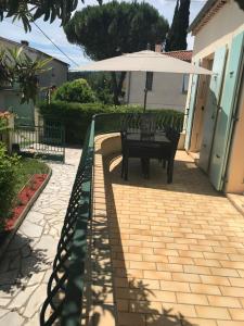 a patio with a bench and an umbrella at Gîte Le Lavandin in Volonne