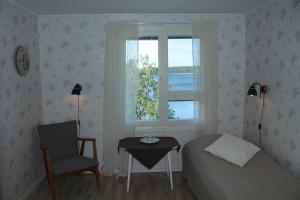 a bedroom with a bed and a chair and a window at Labbnäs Semesterhem in Kimitoön