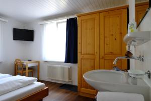 a bathroom with a tub and a bed and a sink at Hotel Frieden in Davos