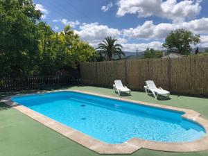 a swimming pool with two chairs and a fence at Casa de Campo Patricia in Priego de Córdoba