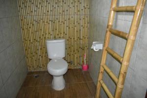 y baño con aseo y pared de bambú. en Medori Putih Homestay, en Uluwatu