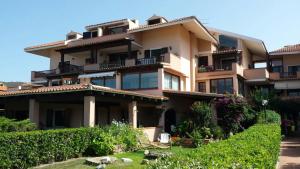 un gran edificio de apartamentos con un jardín delante de él en Lucky Apartment en Golfo Aranci