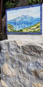 a sign on a stone wall with a picture on it at Acquamarina Accommodation in Massa Lubrense