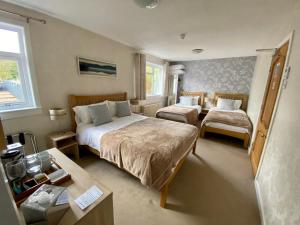 a hotel room with two beds and a table at Coire Glas Guest House in Spean Bridge