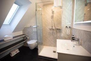 ein Bad mit einer Dusche, einem Waschbecken und einem WC in der Unterkunft Boutique Hotel Poppenbütteler Hof in Hamburg
