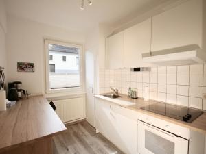 d'une cuisine avec des placards blancs, un évier et une fenêtre. dans l'établissement Apartmenthaus in der Metzstraße, à Bochum