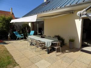 a table with chairs and an umbrella on a patio at Villa Toscana 250 M de la plage in Agon-Coutainville