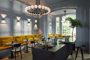 a restaurant with a yellow couch and tables and chairs at stilwerk Hotel Heimhude in Hamburg