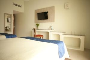 A bed or beds in a room at Hotel Plaza Palenque