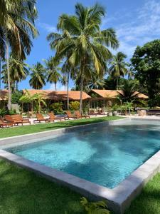 a swimming pool in a resort with palm trees at Quadrado Pousada in São Miguel dos Milagres