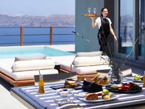 a woman standing in a room with a table of food at Melidonia Suites in Akrotiri