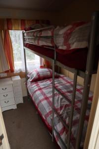 zwei Etagenbetten in einem Zimmer mit Fenster in der Unterkunft Kimberley Lane Static, Cornwall in Gwennap