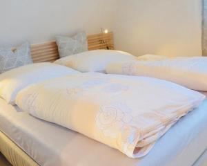 two beds with white sheets with a rose on them at Ferienwohnung Bolle in Hooksiel