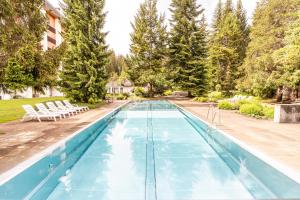 a pool with blue water in a yard with trees at Rancho Apartment in Laax