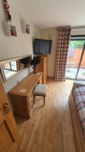 Habitación con escritorio, TV y sofá. en Ardconnel Apartment, en Inverness