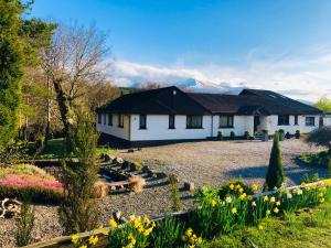 a house with a garden with flowers in front of it at Distant Hills Guest House in Spean Bridge