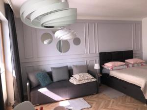 a room with a couch and a bed and a chandelier at Apartament Bellamore in Gdańsk