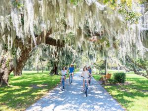 two people walking down a street next to trees at Jekyll Island Club Resort in Jekyll Island