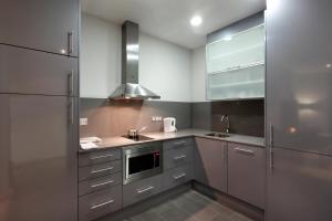 una cocina con armarios de acero inoxidable y fregadero en Fisa Rentals Gran Via Apartments en Barcelona