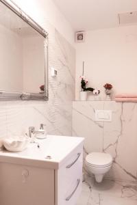 a white bathroom with a toilet and a sink at SunVilla with hot tub in Koper